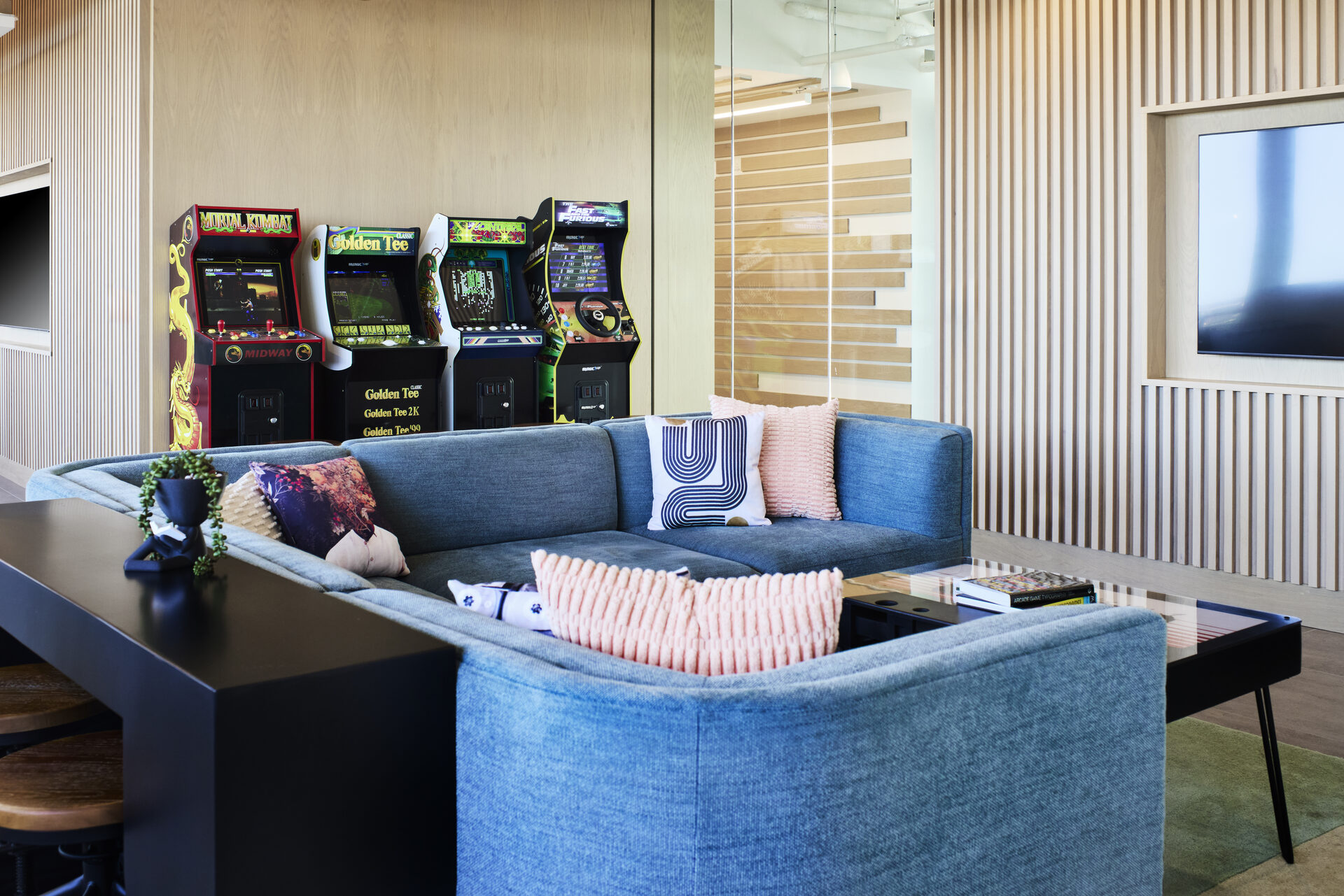 A modern game room at The 202 apartment building, featuring arcade games and comfortable seating, designed for entertainment and relaxation.