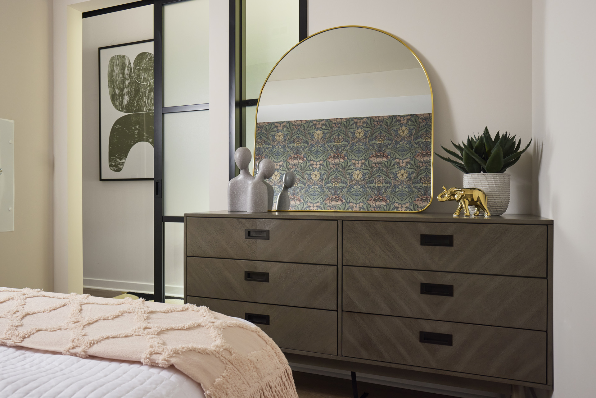 An elegantly designed bedroom at The 202, featuring a sleek dresser with a large mirror on top.